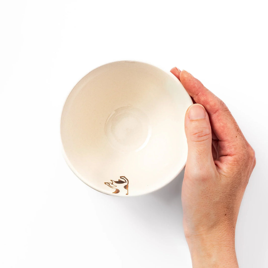 Cream-colored rice bowl with a calico hanging cat, butterfly, and playful paw prints on the outside and inner rim.