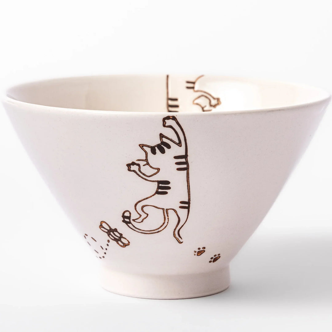 Cream-colored rice bowl with a striped hanging cat, butterfly, and dotted paw prints on the outer and inner surface.