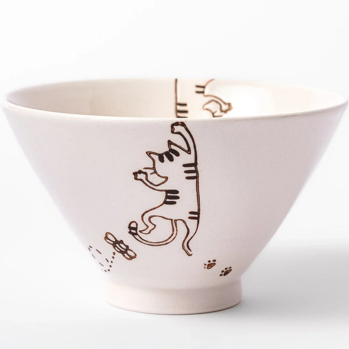 Cream-colored rice bowl with a striped hanging cat, butterfly, and dotted paw prints on the outer and inner surface.