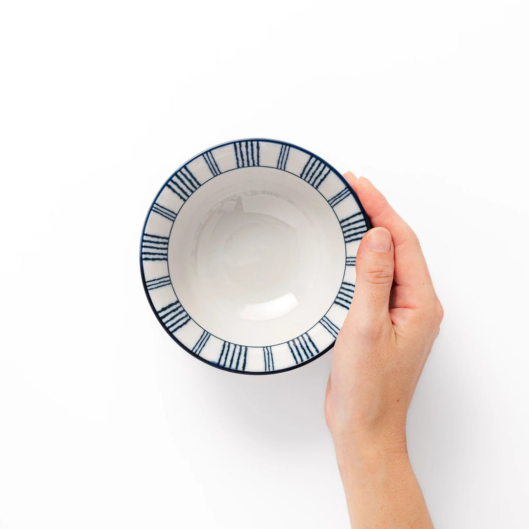 Japanese porcelain rice bowl with fine indigo vertical stripes and terracotta base in minimalist design.