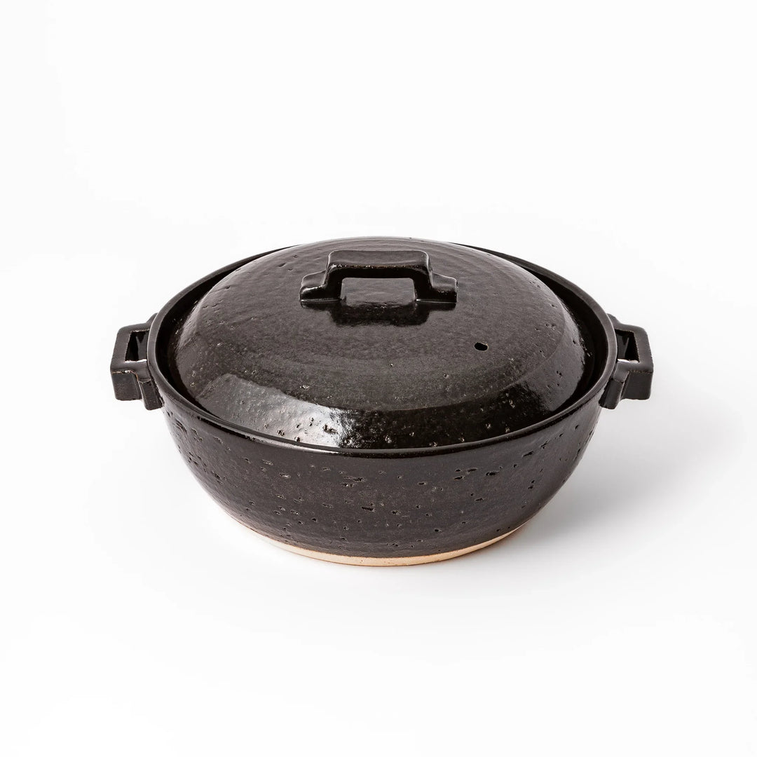 Black Japanese ceramic donabe pot with lid and side handles for simmering and hot pot cooking