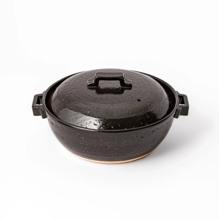 Black Japanese ceramic donabe pot with lid and side handles for simmering and hot pot cooking