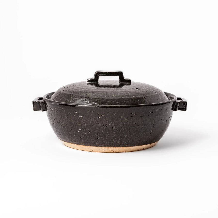 Black Japanese ceramic donabe pot with lid and side handles for simmering and hot pot cooking