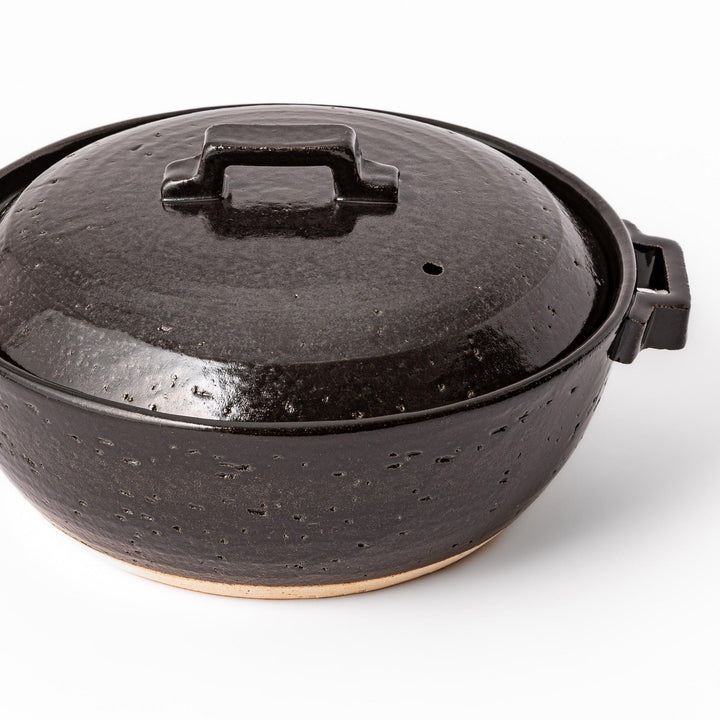 Black Japanese ceramic donabe pot with lid and side handles for simmering and hot pot cooking