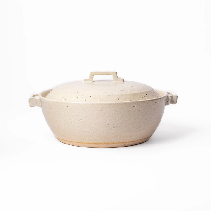 White Japanese donabe with a vented lid and side handles made of rustic handcrafted ceramic