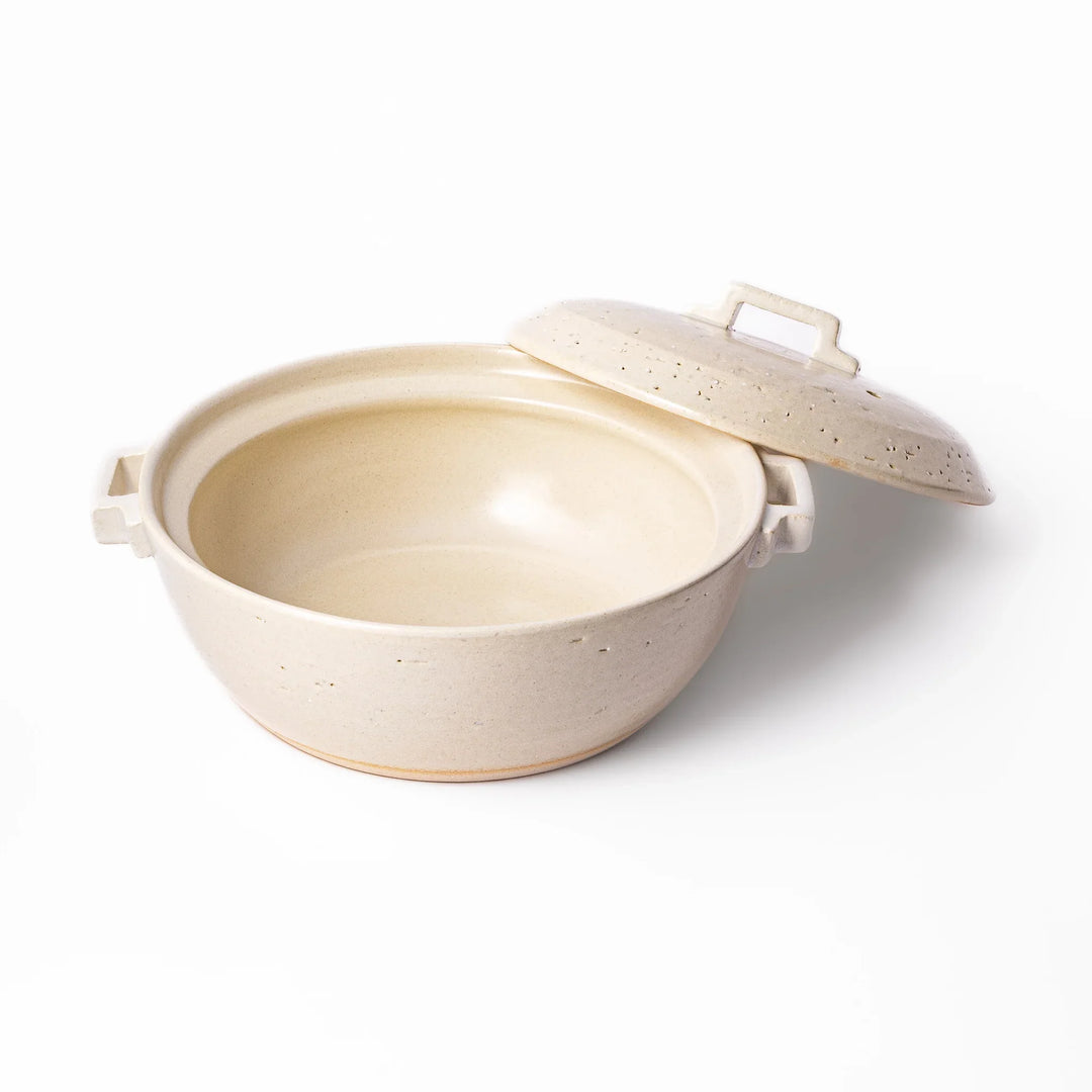 White Japanese donabe with a vented lid and side handles made of rustic handcrafted ceramic