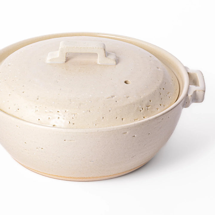 White Japanese donabe with a vented lid and side handles made of rustic handcrafted ceramic