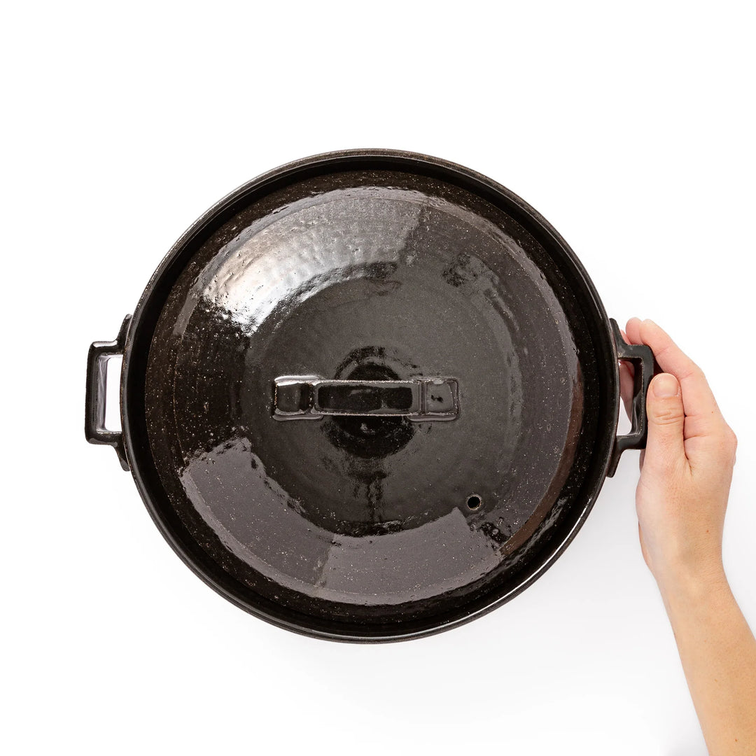 Black Japanese ceramic donabe with a fitted lid and side handles for family size hot pot and stovetop cooking