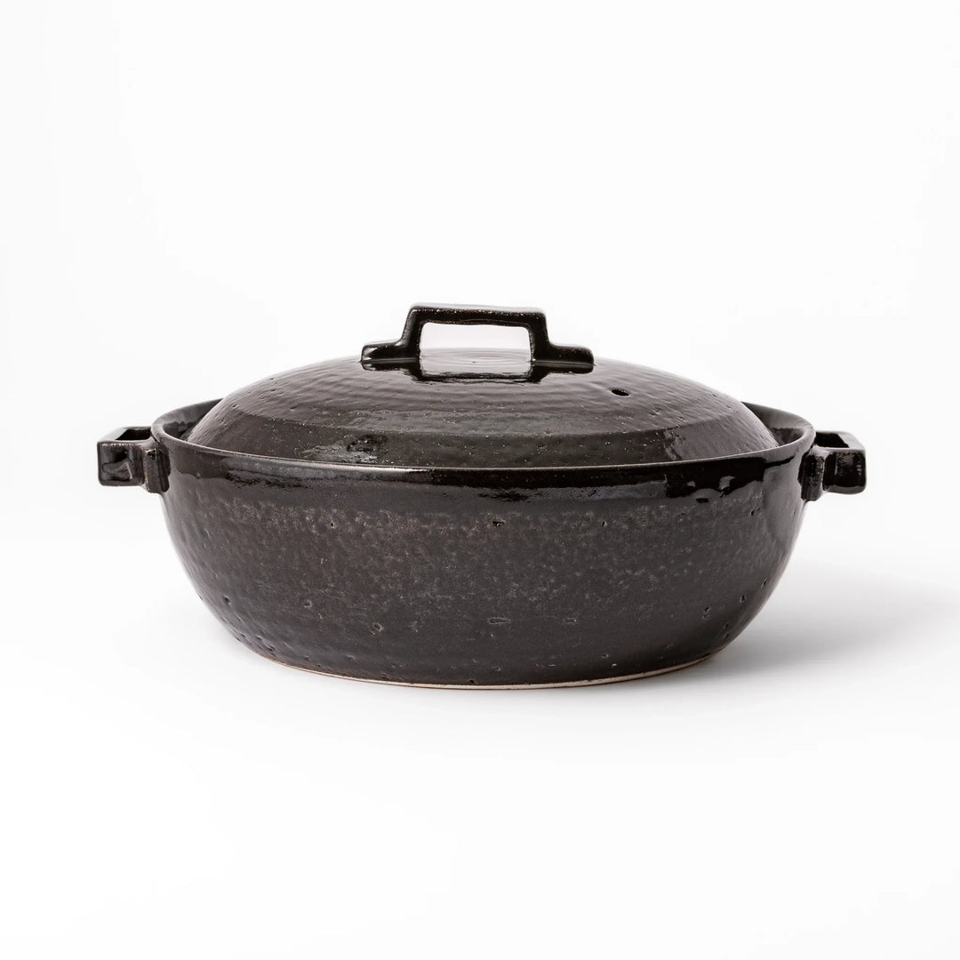Black Japanese ceramic donabe with a fitted lid and side handles for family size hot pot and stovetop cooking