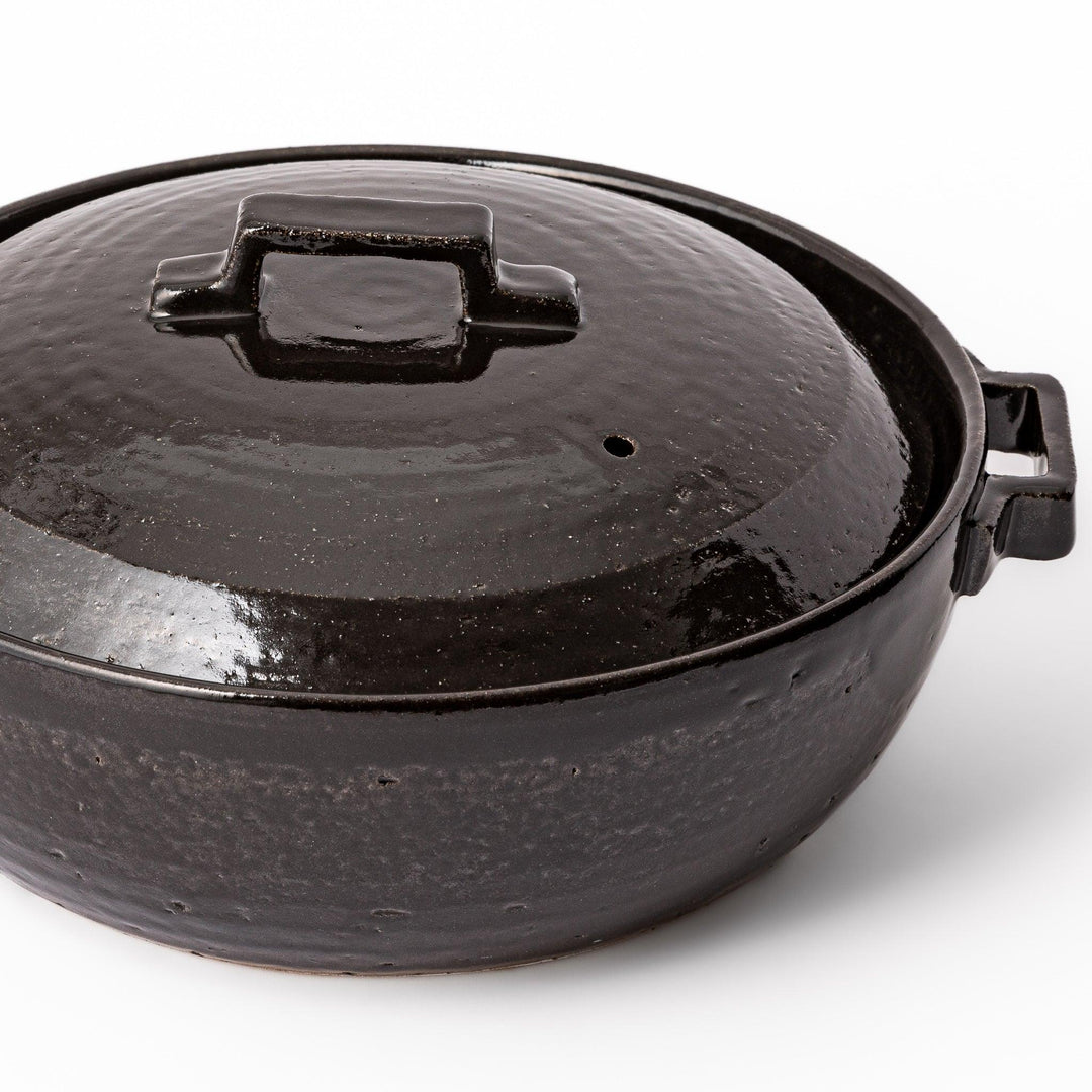 Black Japanese ceramic donabe with a fitted lid and side handles for family size hot pot and stovetop cooking