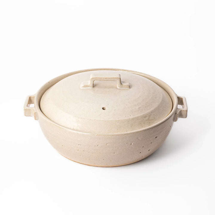 Beige Japanese ceramic family size donabe with a fitted lid and side handles for stovetop cooking and hot pot meals