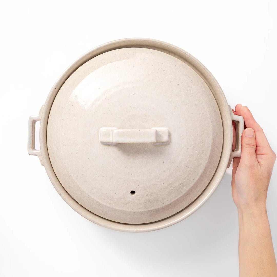 Beige Japanese ceramic family size donabe with a fitted lid and side handles for stovetop cooking and hot pot meals
