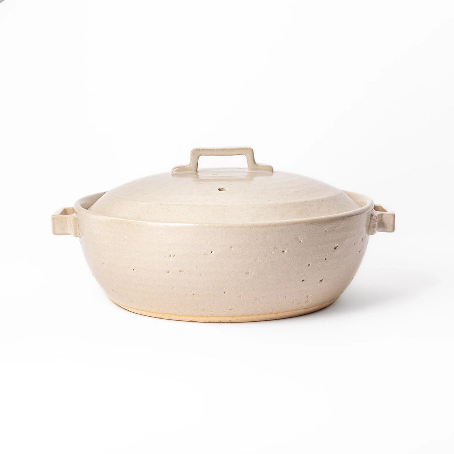 Beige Japanese ceramic family size donabe with a fitted lid and side handles for stovetop cooking and hot pot meals