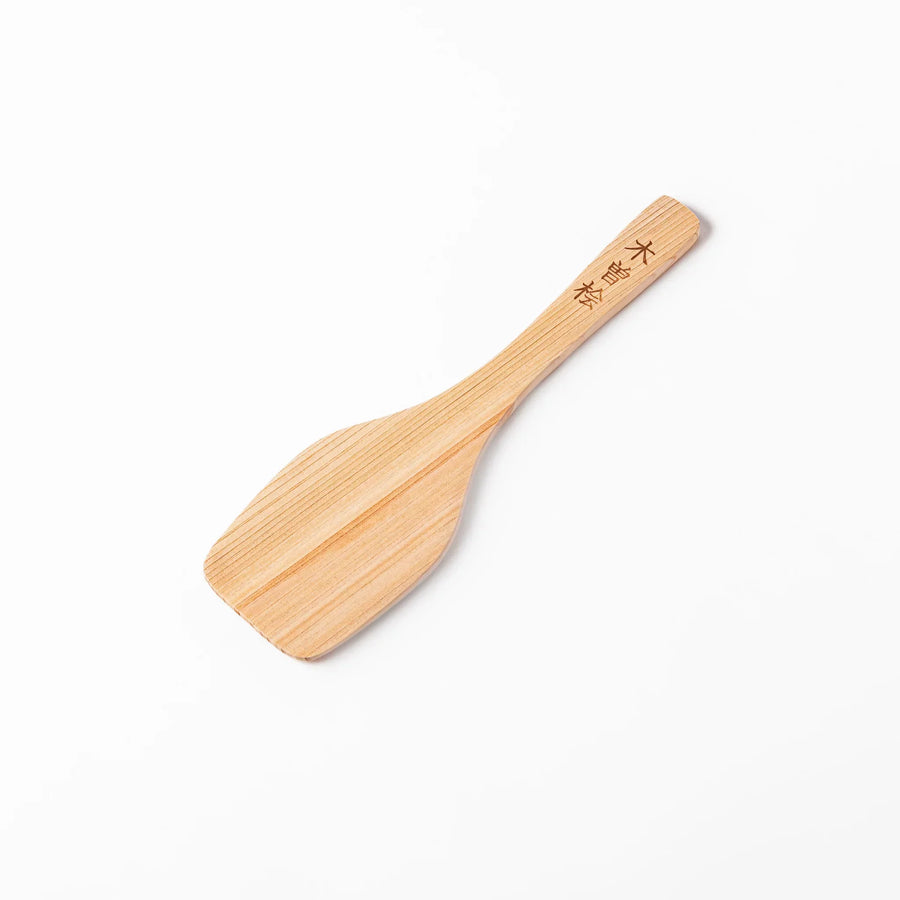 Compact hinoki wood spatula with flat angled edge and engraved handle for straining flipping and serving.