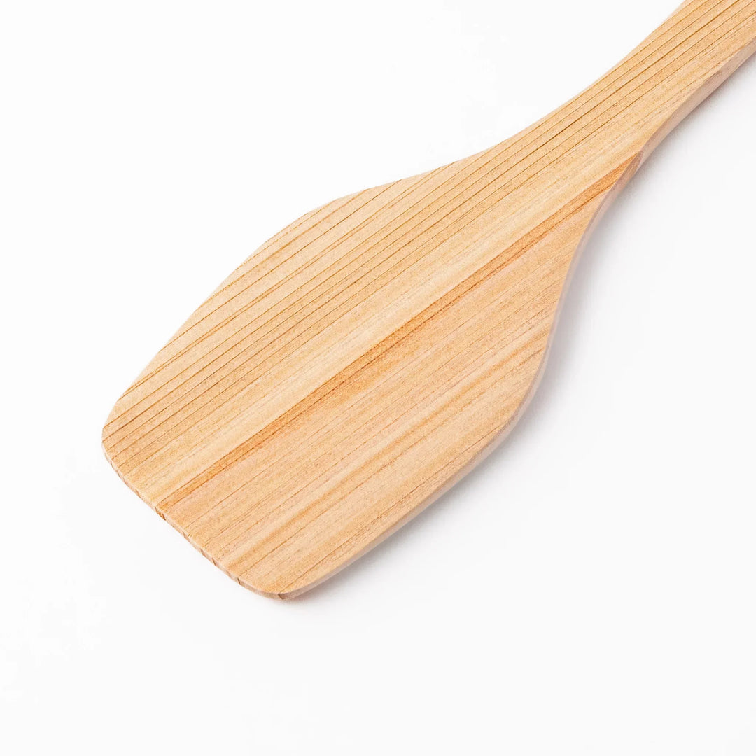 Compact hinoki wood spatula with flat angled edge and engraved handle for straining flipping and serving.