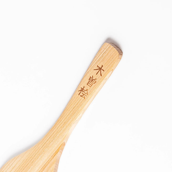 Compact hinoki wood spatula with flat angled edge and engraved handle for straining flipping and serving.