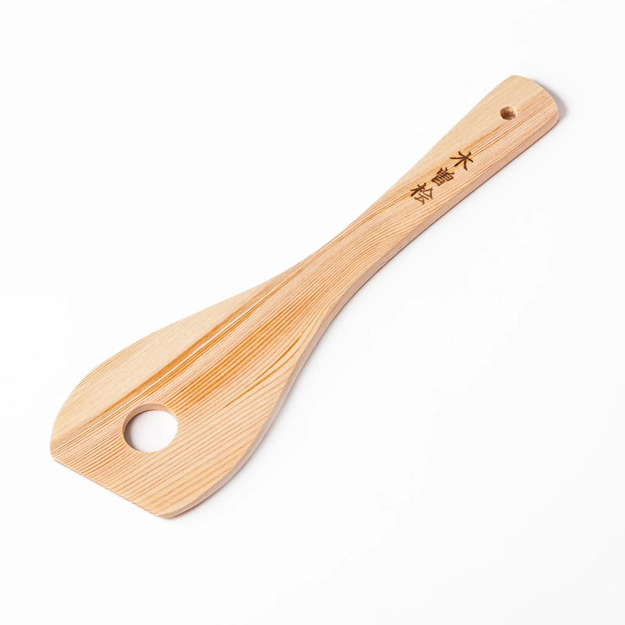 Hinoki wood slotted spatula with circular cutout and engraved handle for stirring and draining food.