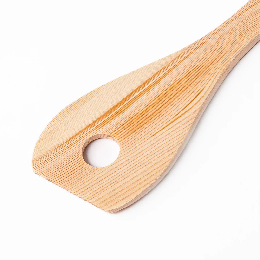 Hinoki wood slotted spatula with circular cutout and engraved handle for stirring and draining food.