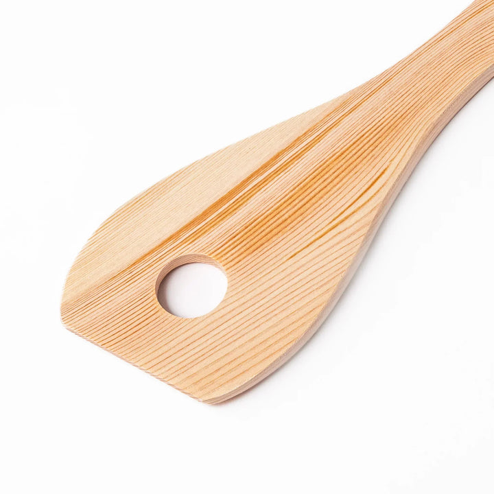 Hinoki wood slotted spatula with circular cutout and engraved handle for stirring and draining food.