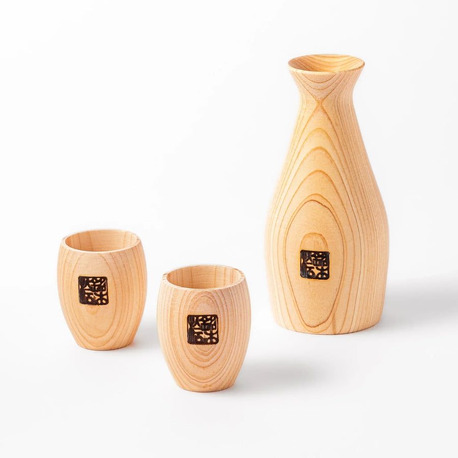 Hinoki wood sake set with carafe and two cups featuring burnt in designs for elegant Japanese sake rituals.