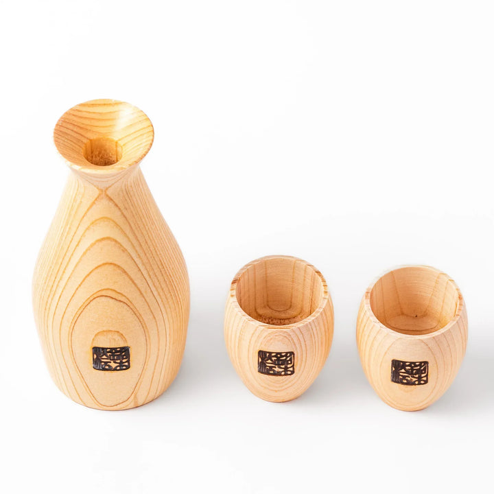 Hinoki wood sake set with carafe and two cups featuring burnt in designs for elegant Japanese sake rituals.
