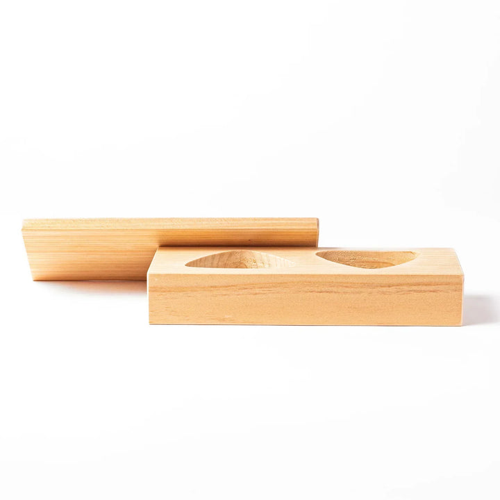 Hinoki wood onigiri mold with two triangle cavities and lid for shaping aromatic Japanese rice balls.