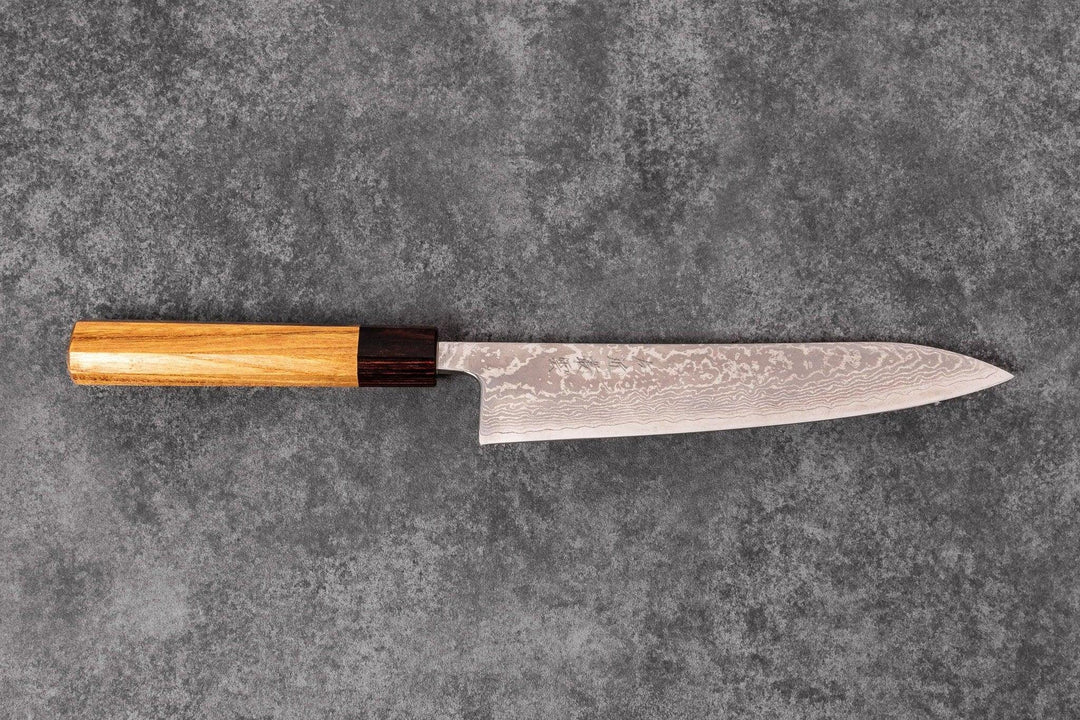 Japanese Damascus chef knife with a wooden handle displayed on a textured gray surface