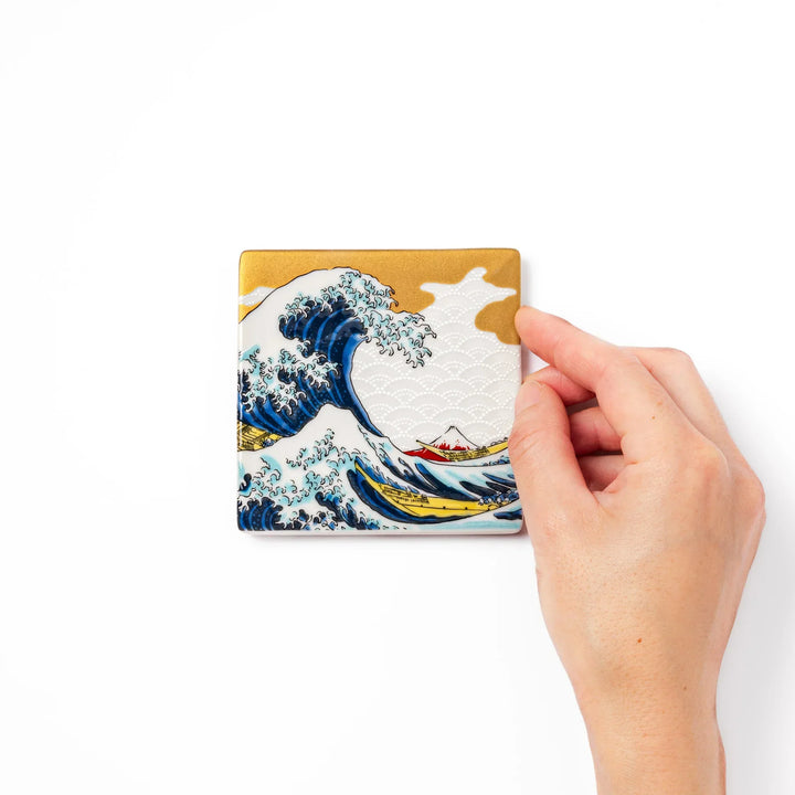 Square Japanese ceramic coaster with Hokusai Great Wave design featuring blue waves golden sky and Mt Fuji.