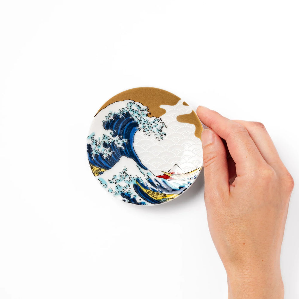 Round Japanese ceramic sauce dish with Hokusai Great Wave design showing blue waves golden sky and Mt Fuji.