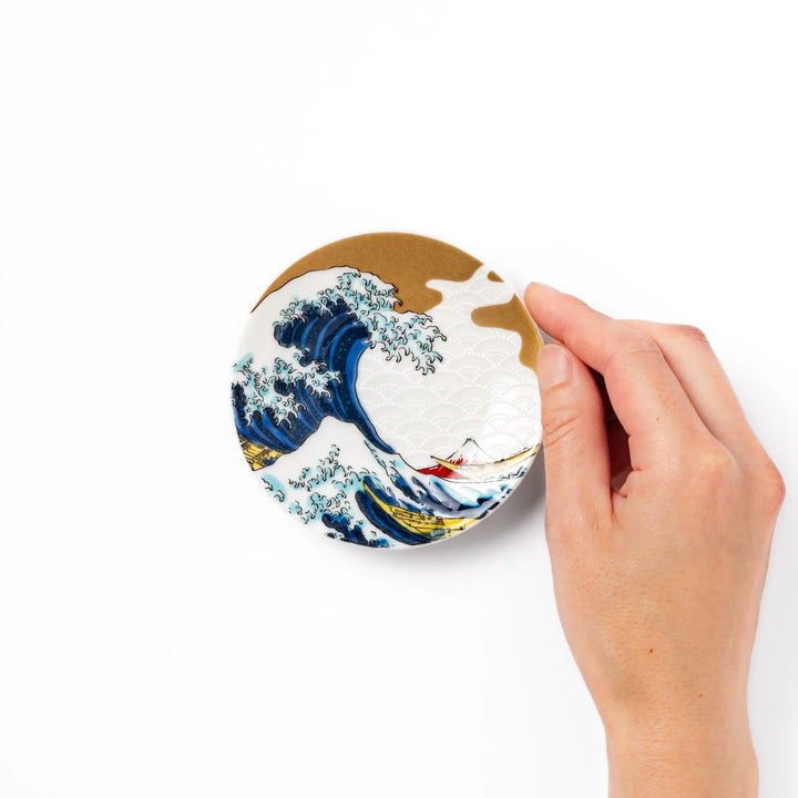 Round Japanese ceramic sauce dish with Hokusai Great Wave design showing blue waves golden sky and Mt Fuji.