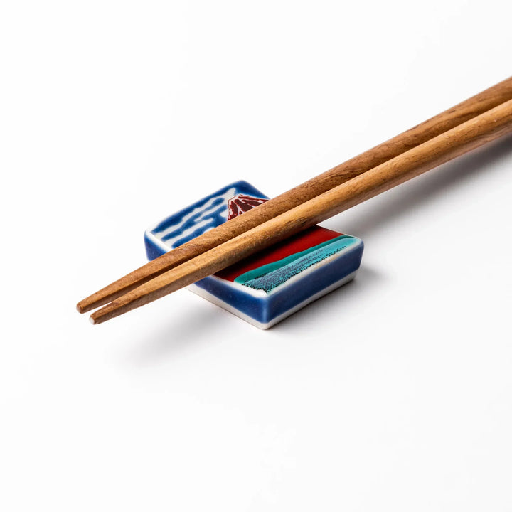 Rectangular Japanese ceramic chopstick rest with Hokusai Red Fuji design showing red mountain and blue sky.