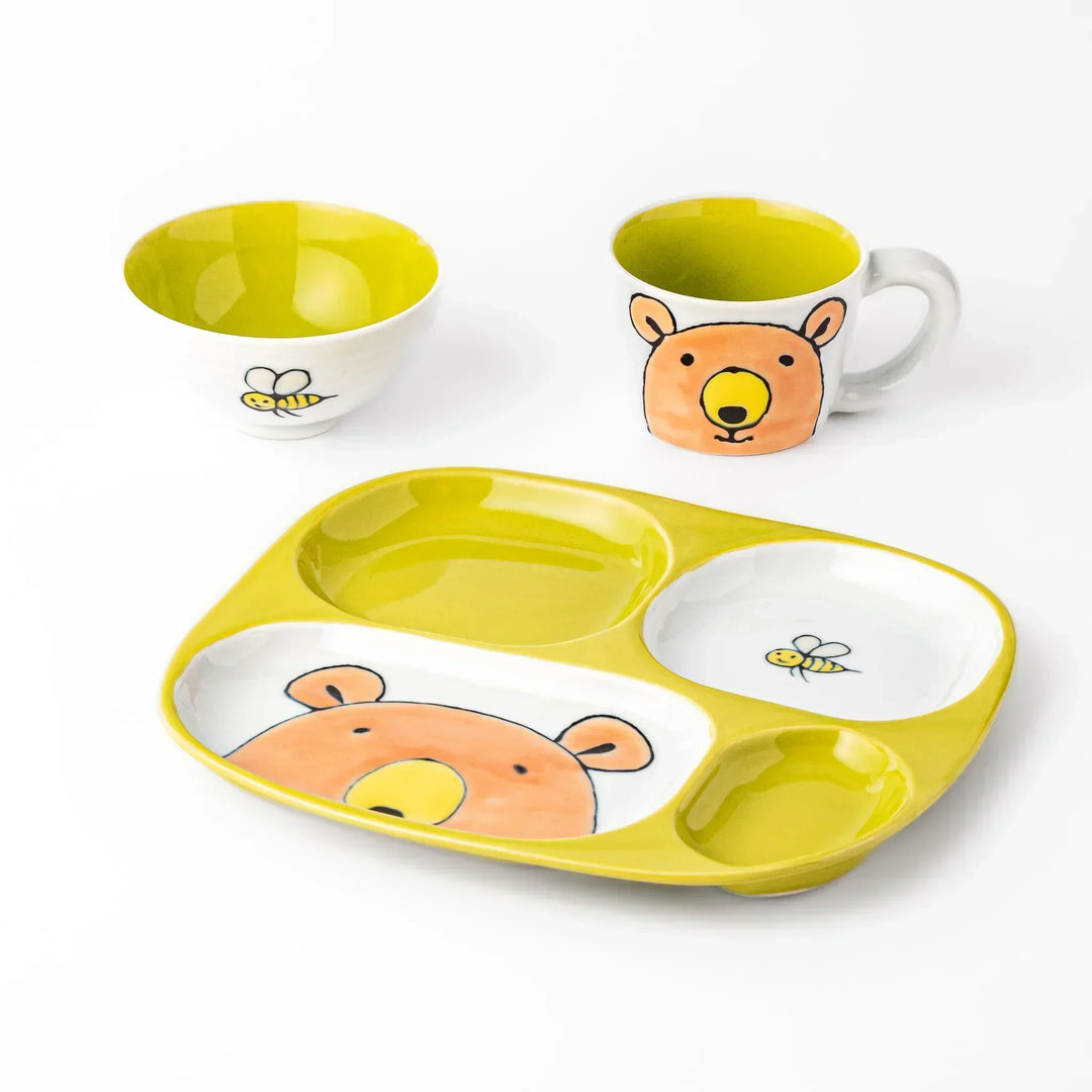 White ceramic kids plate, mug, and rice bowl set featuring honey bear face and bee motif, chartreuse interior