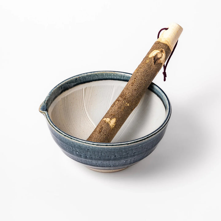Indigo Japanese suribachi mortar with cream grooved interior and wooden pestle for grinding sesame seeds.