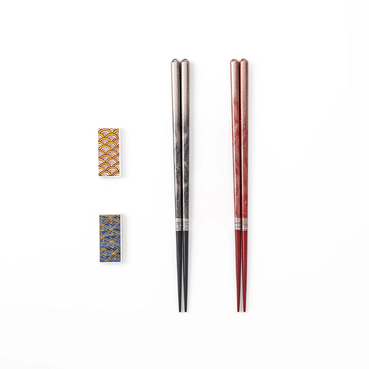 A pair of black and red lacquer Japanese chopsticks with two rectangular ceramic chopstick rests featuring traditional patterns