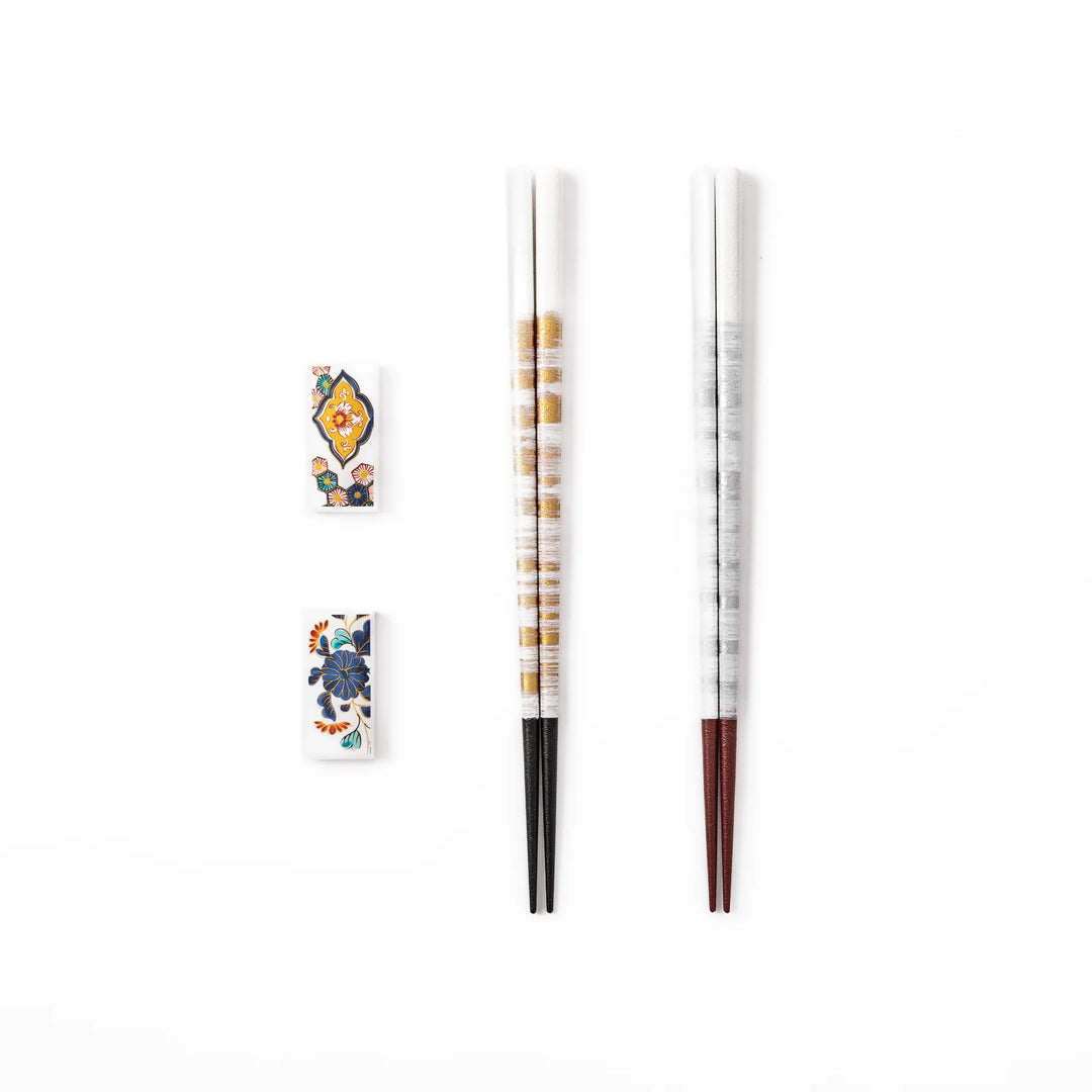 A pair of gold and silver textured Japanese chopsticks with two rectangular ceramic chopstick rests featuring floral patterns