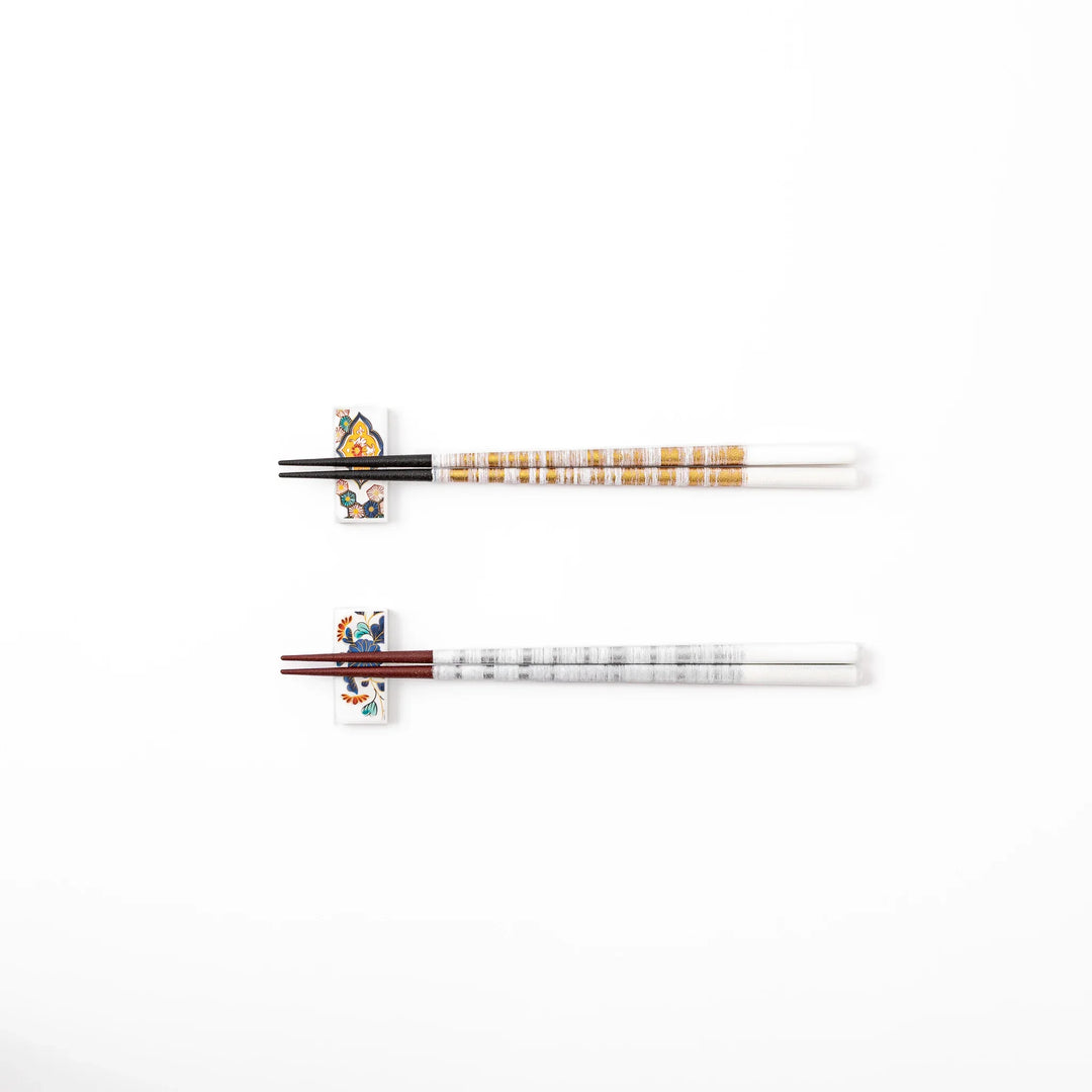 A pair of gold and silver textured Japanese chopsticks with two rectangular ceramic chopstick rests featuring floral patterns