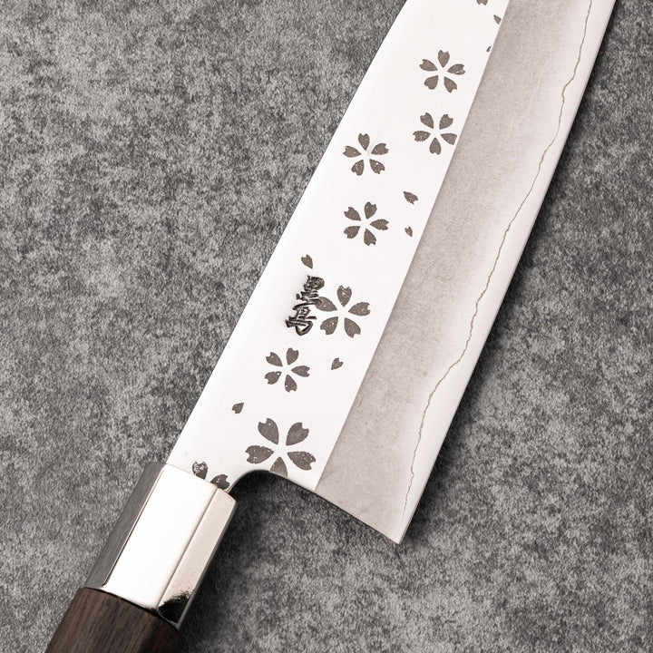 Japanese kitchen knife with cherry blossom cutout blade and dark wooden handle for precise cutting.