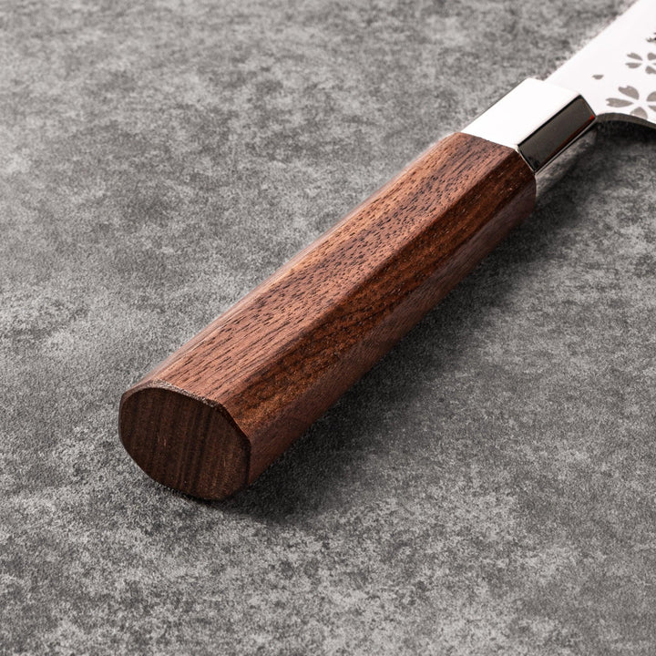 Japanese kitchen knife with cherry blossom cutout blade and dark wooden handle for precise cutting.