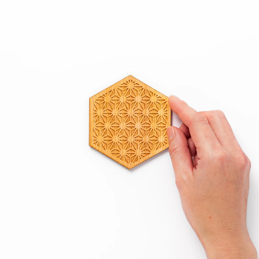 Hexagon hinoki wood coaster with engraved hemp star pattern on a white background.