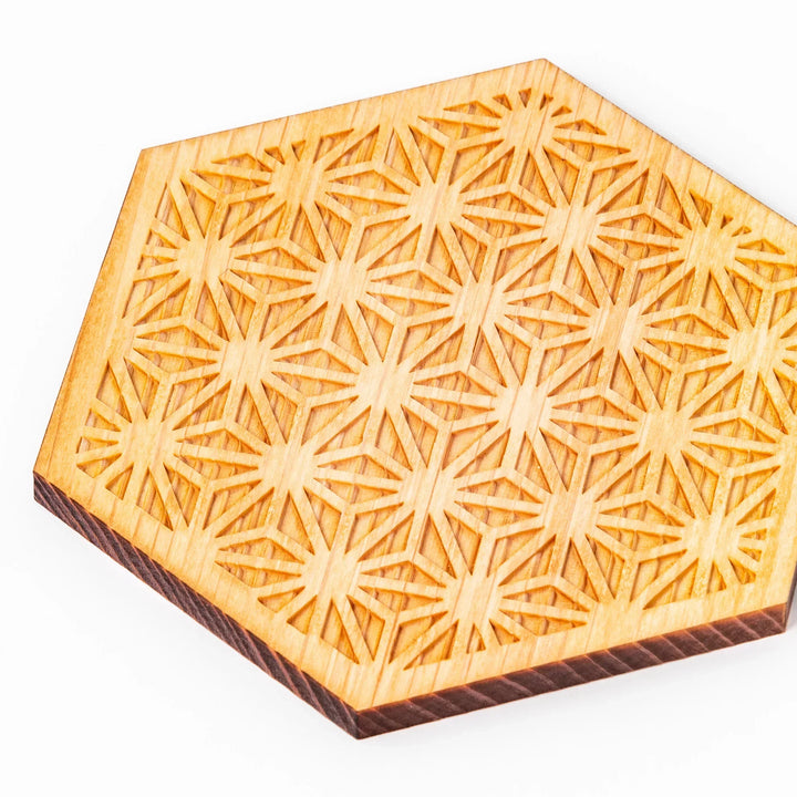 Hexagon hinoki wood coaster with engraved hemp star pattern on a white background.