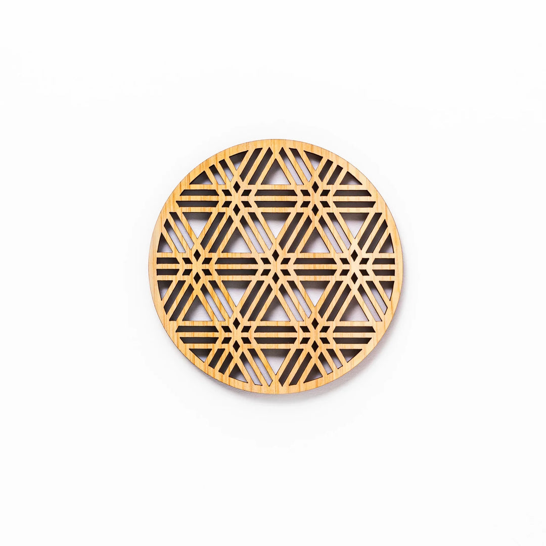 Round hinoki wood coaster with a sesame lattice cutout pattern, showcasing intricate geometric Japanese design.