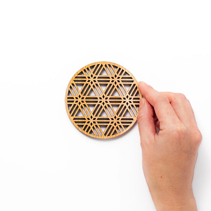 Round hinoki wood coaster with a sesame lattice cutout pattern, showcasing intricate geometric Japanese design.