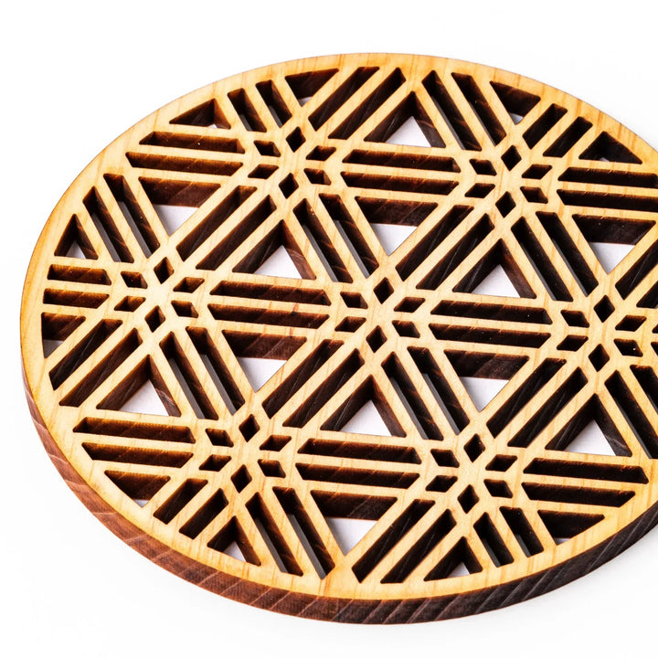Round hinoki wood coaster with a sesame lattice cutout pattern, showcasing intricate geometric Japanese design.