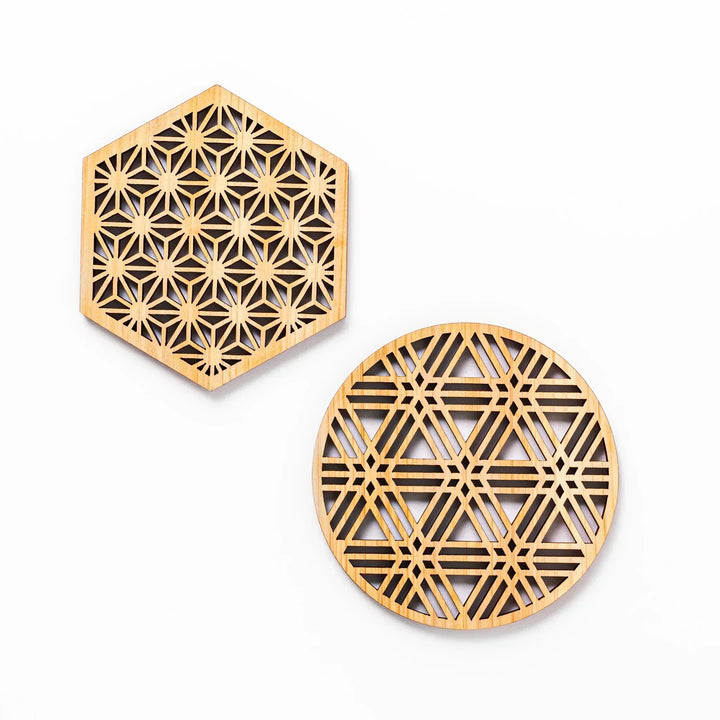 Hinoki wood coasters with intricate geometric cutout patterns, one hexagon and one round, displayed on a white background.