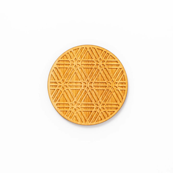 Round hinoki wood coaster with engraved sesame lattice pattern, featuring warm natural grain and a finely detailed geometric design.