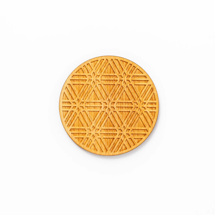 Round hinoki wood coaster with engraved sesame lattice pattern, featuring warm natural grain and a finely detailed geometric design.