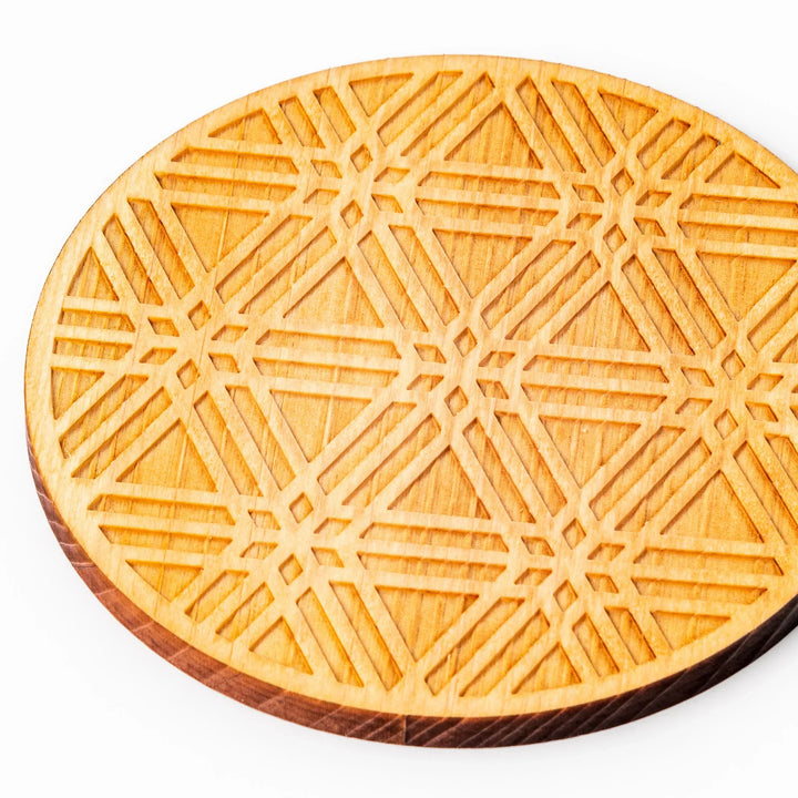 Round hinoki wood coaster with engraved sesame lattice pattern, featuring warm natural grain and a finely detailed geometric design.