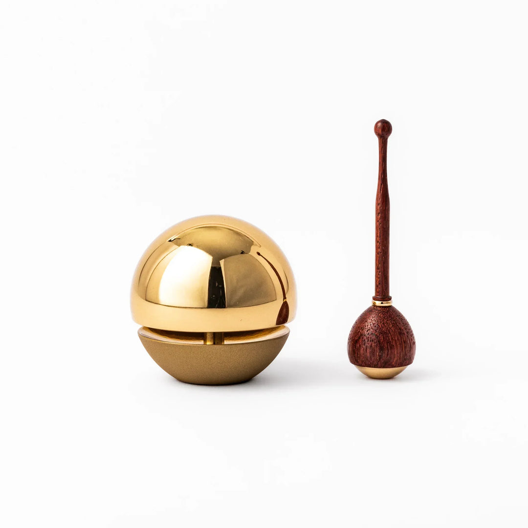 Japanese meditation and prayer chime with golden dome bell and wooden striker for mindfulness rituals.