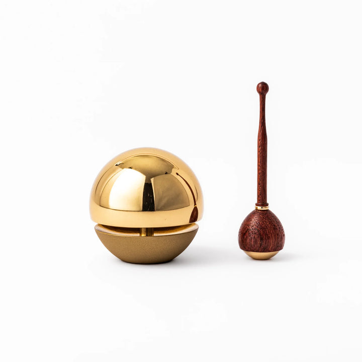 Japanese meditation and prayer chime with golden dome bell and wooden striker for mindfulness rituals.