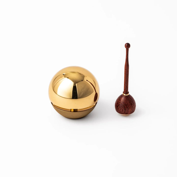 Japanese meditation and prayer chime with golden dome bell and wooden striker for mindfulness rituals.